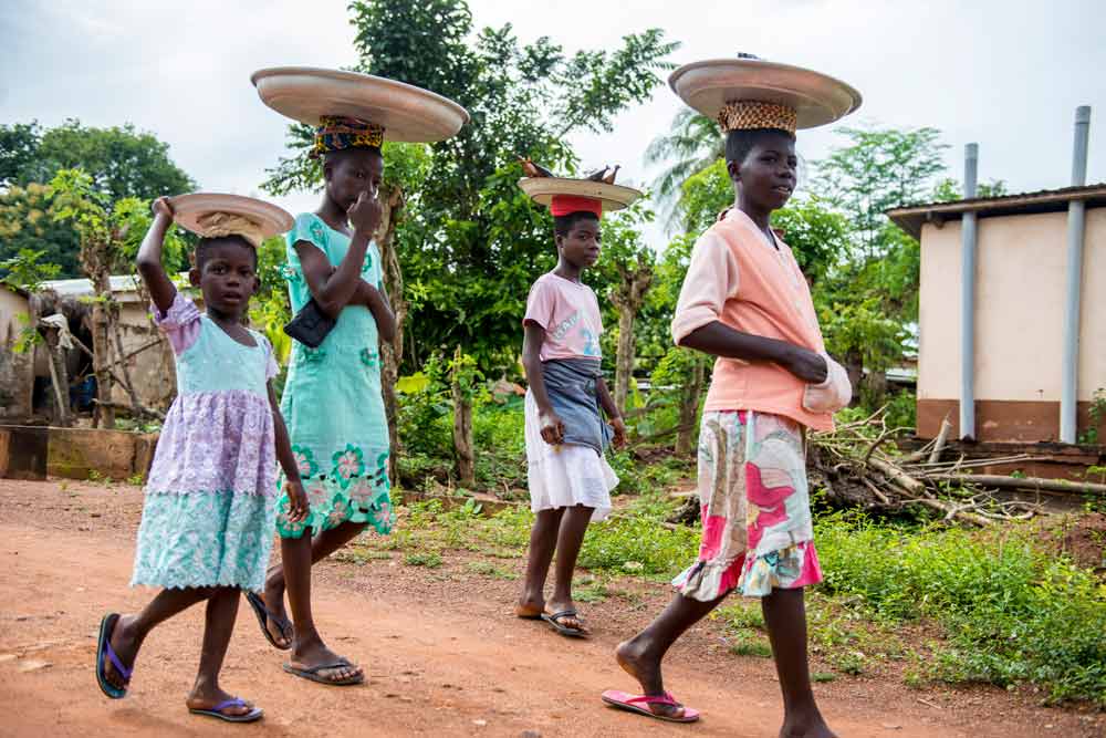 young women carry baskets on their heads