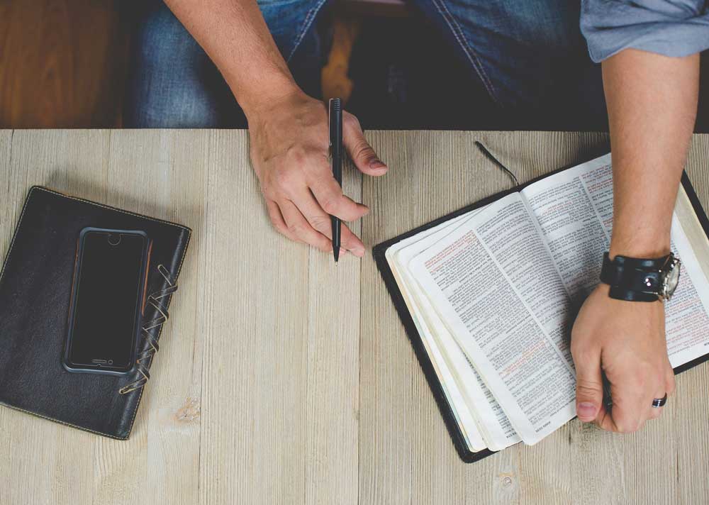 Guy reading his Bible with a notebook next to him