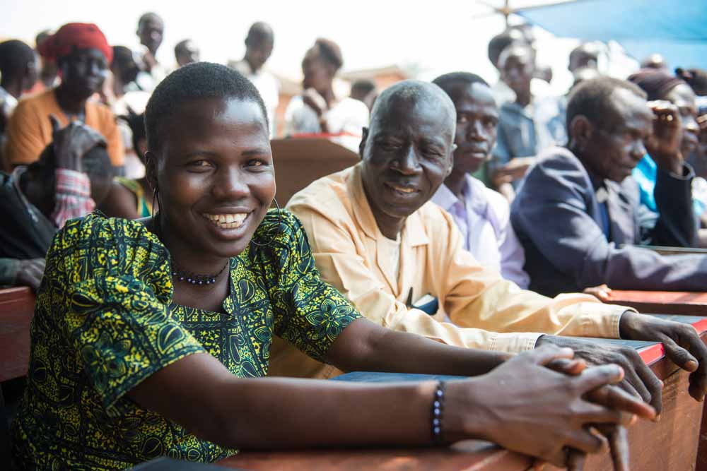 Woman sitting in a row with others at the Baka Scripture Dedication