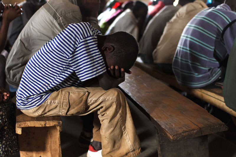 boy with head in hands, praying in church