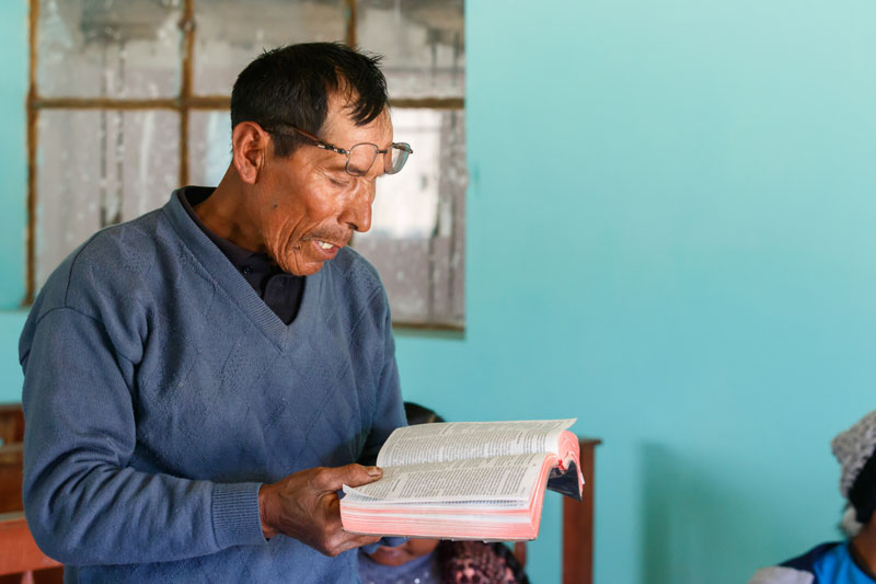 Man reads to community group from the Quechua Bible.