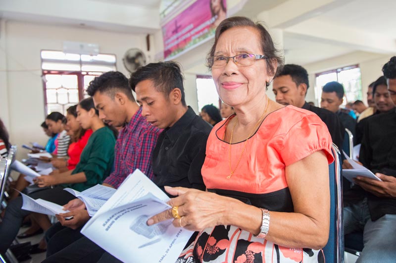 Woman holding materials in a gathering.