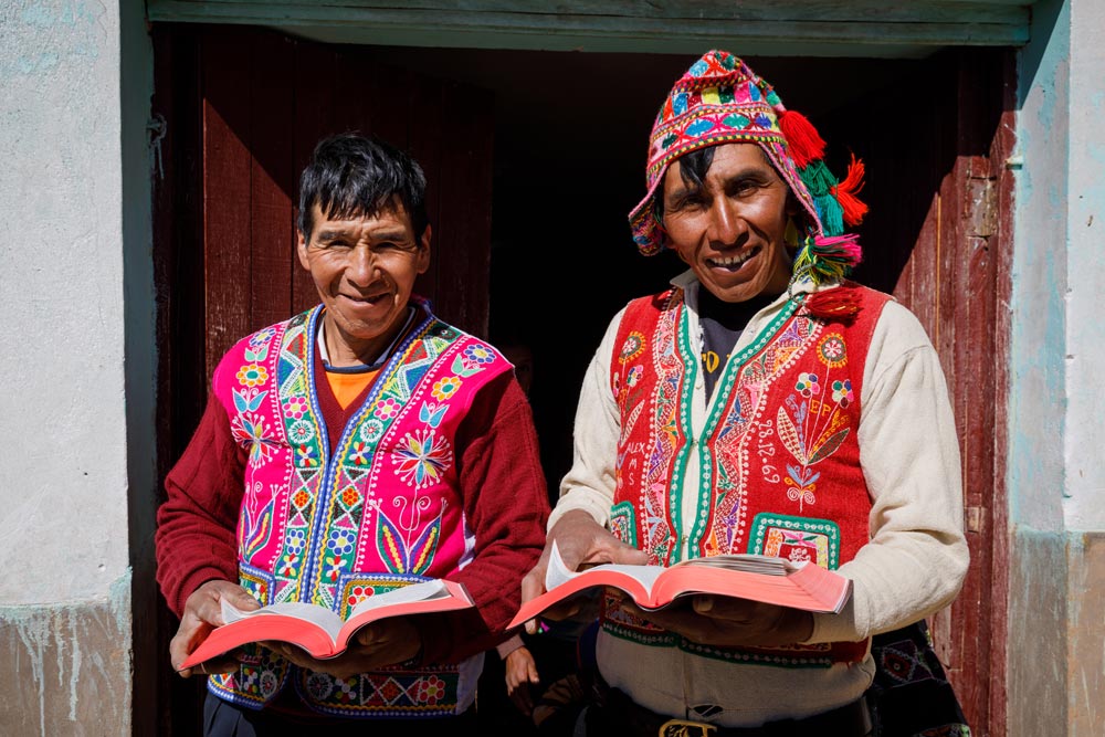 Two Peruvian men holding open Bibles